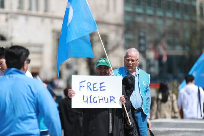 A man holds a sign that says 'Free Uighur' as part of a protest against China's actions in the Xinjiang Uyghur Autonomous Region.